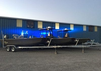 3 custom green law enforcement boats with their blue lights on