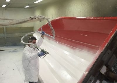 man spray painting a boat white
